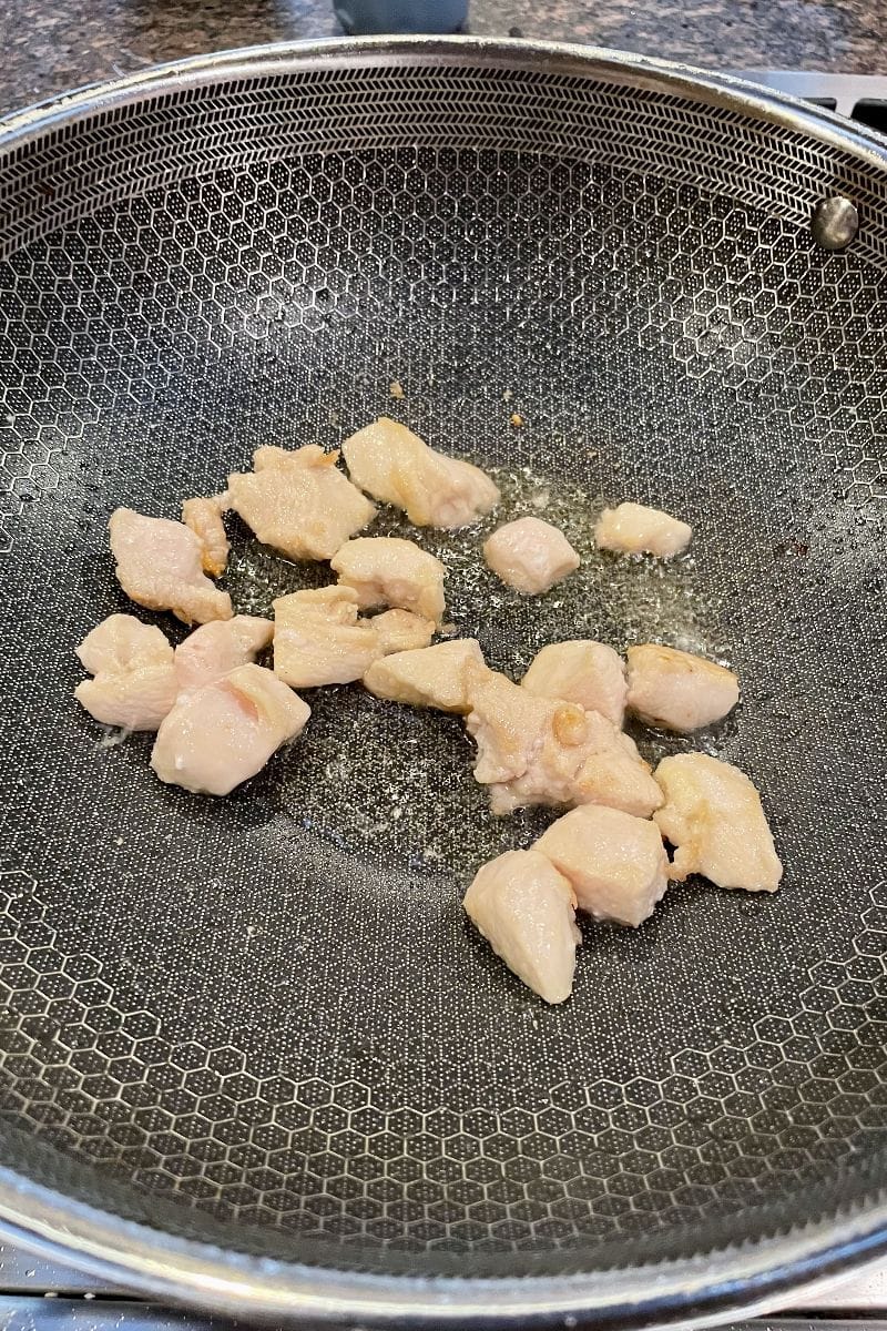 Frying chicken pieces in a wok.