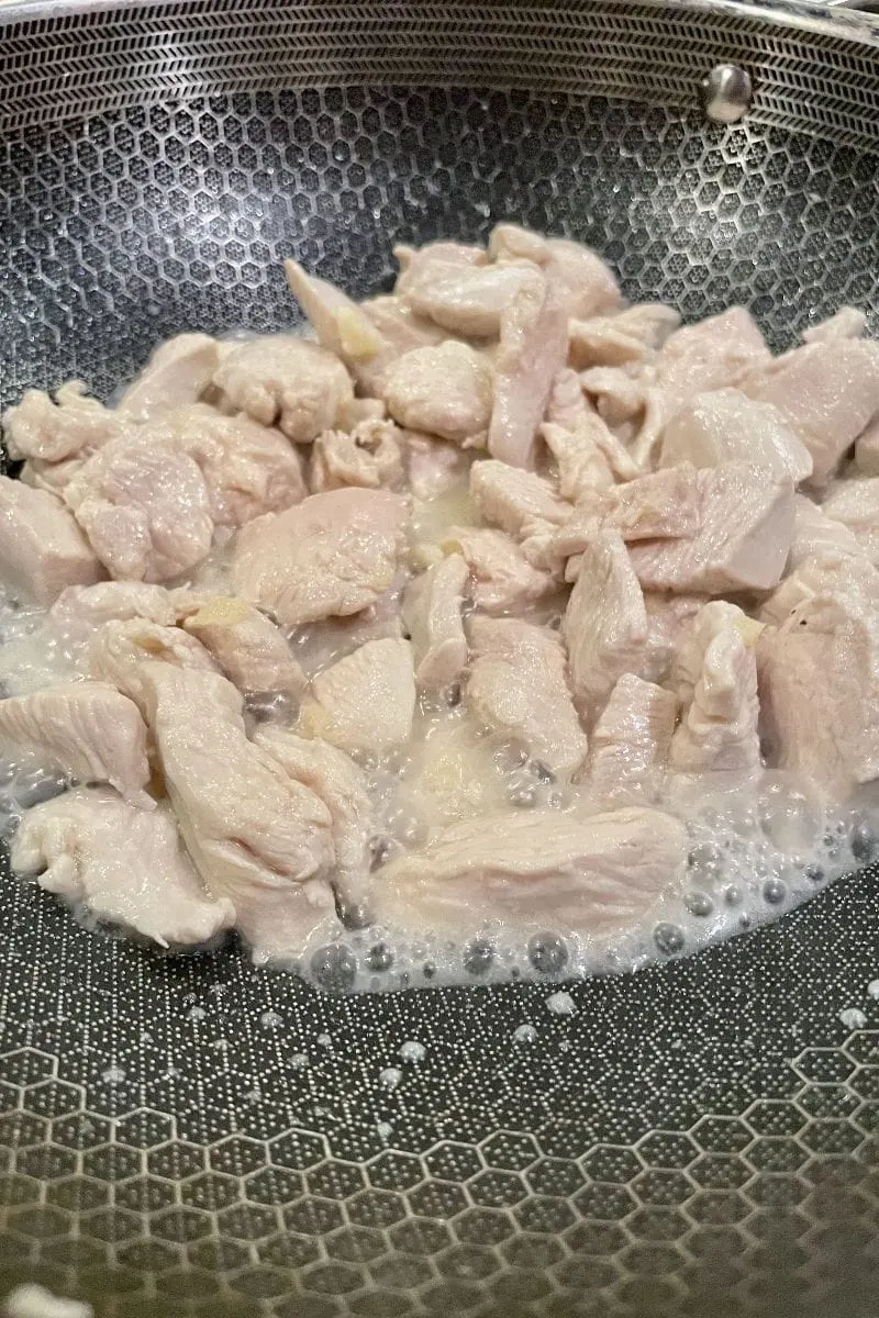 Chicken breast chunks, stir frying in pan.