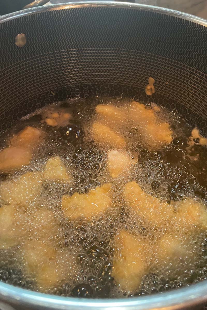 Battered chicken pieces frying in oil. 