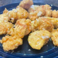 Chinese honey chicken prepared on blue plate.