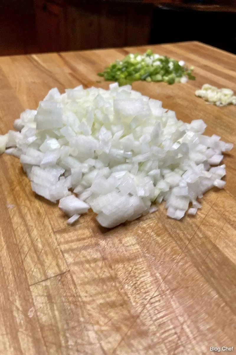 Chopped onions and garlic on a cutting board. 