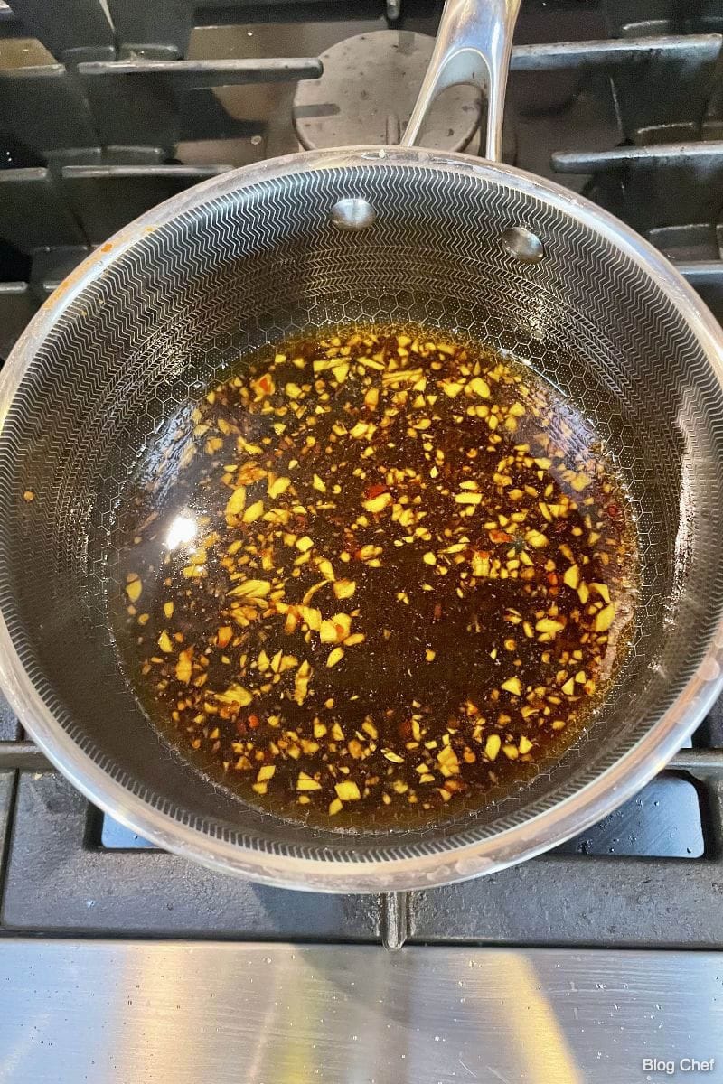 Sauce for sesame noodles with chicken cooking in saucepan. 
