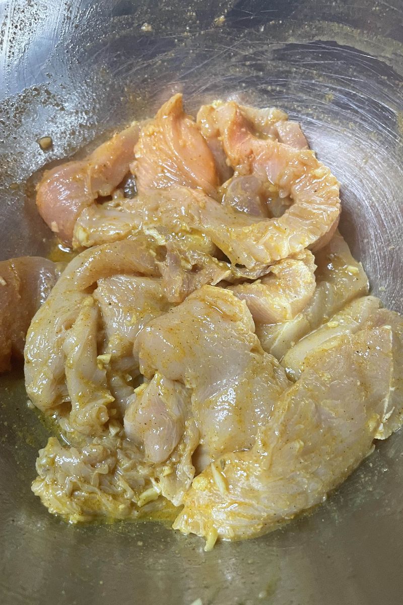 Raw chicken marinating to make chicken shawarma.