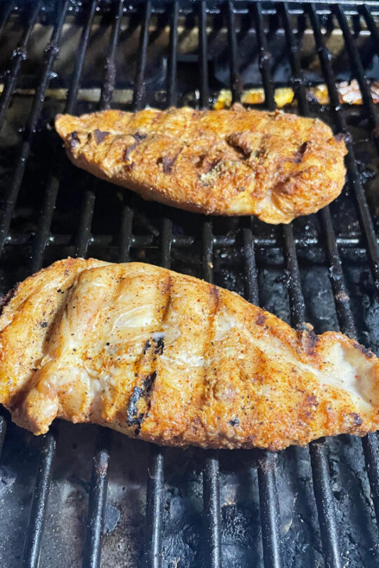 Chicken with Cajun seasoning on grill.