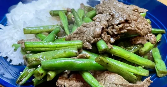 Close up view of black pepper beef prepared with green beans.