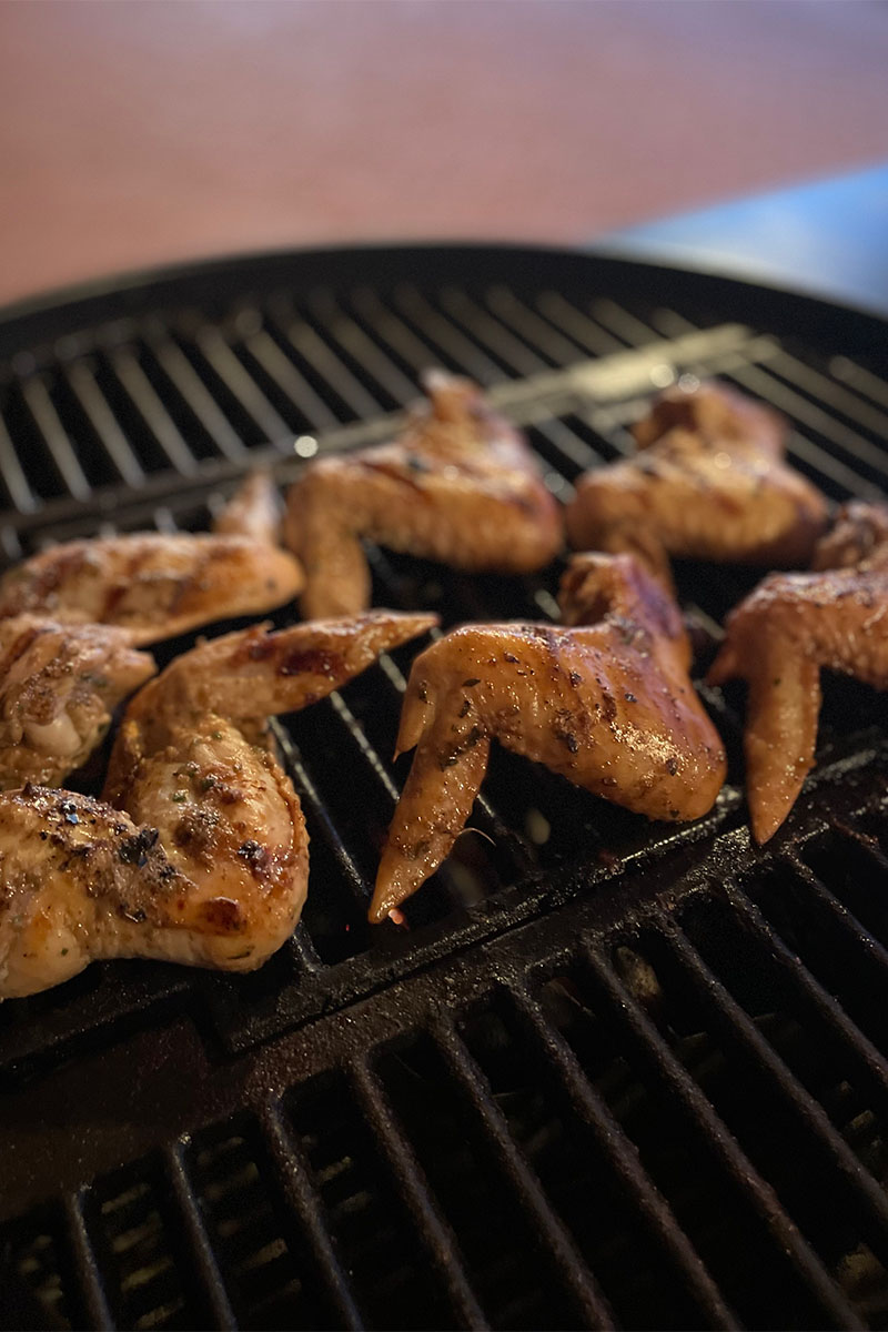 Marinated jerk chicken wings on grill.