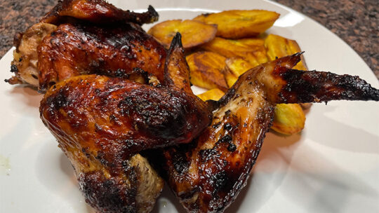 Close up view of jerk chicken on plate with plantains.