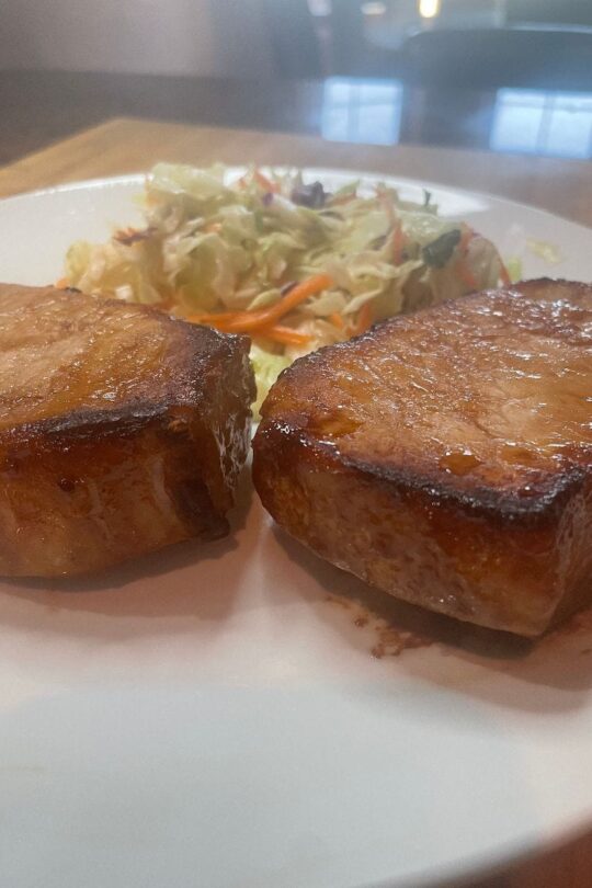 Prepared teriyaki pork chops on plate with Asian slaw.