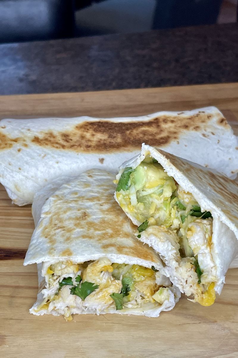 Prepared grilled chicken avocado wraps on cutting board. 