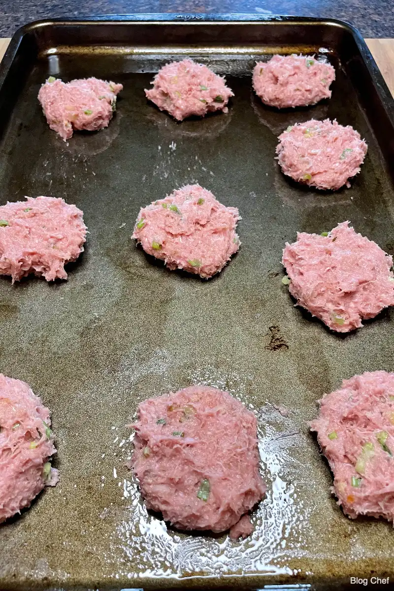 Uncooked patties for Chinese sliders on a baking sheet.