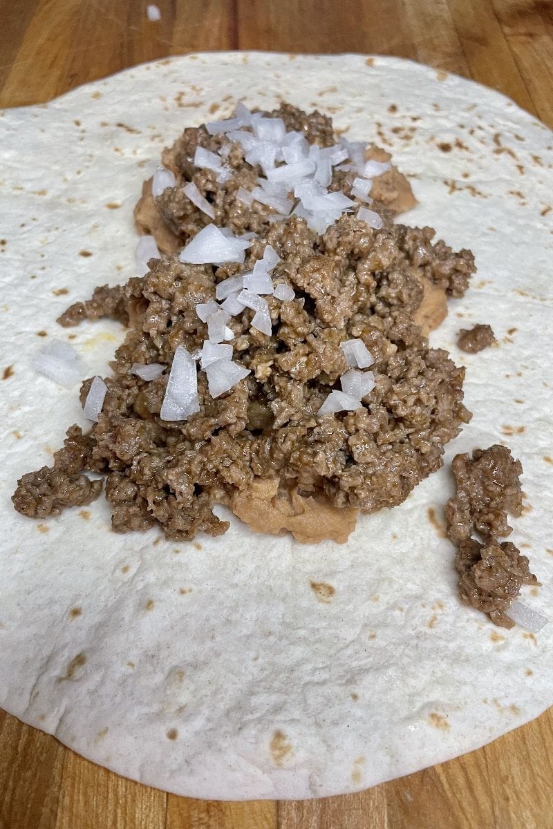 Flour tortilla, beans, and meat for Taco Bell enchirito recipe.