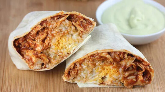 Close-up view of prepared Taco Bell chicken burrito, cut in half.