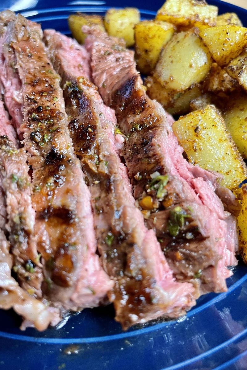 Flank steak prepared with Qdoba steak marinade recipe, along with potatoes on plate.
