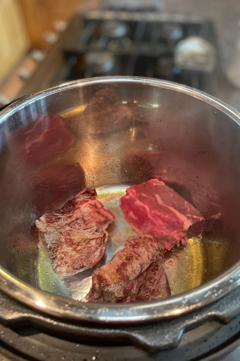 Top view of chuck roast in Instant Pot, browning on saute mode.