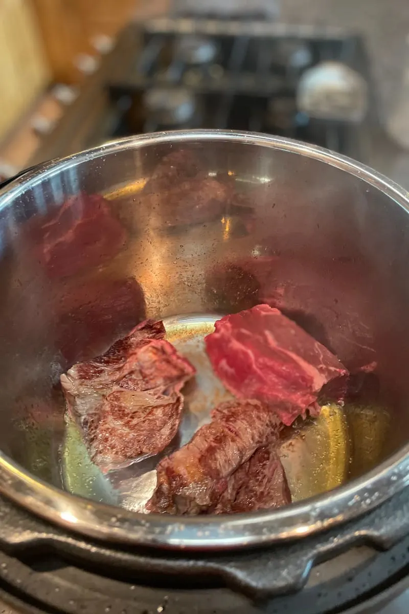 Top view of chuck roast in Instant Pot, browning on saute mode.