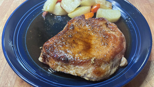 Prepared balsamic pork chop on plate with roasted vegetables.
