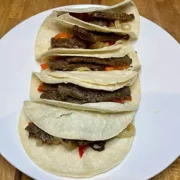 Carne asada prepared and stuffed into soft corn tortillas.