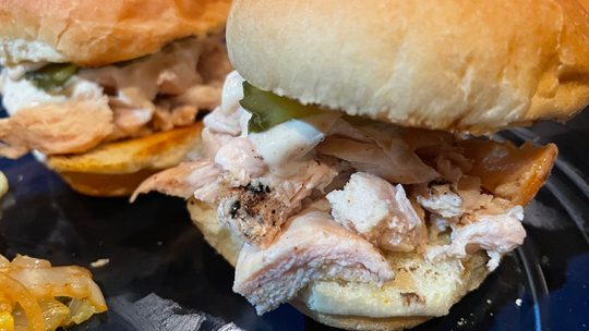 Close up view of grilled chicken sliders with white barbecue sauce.