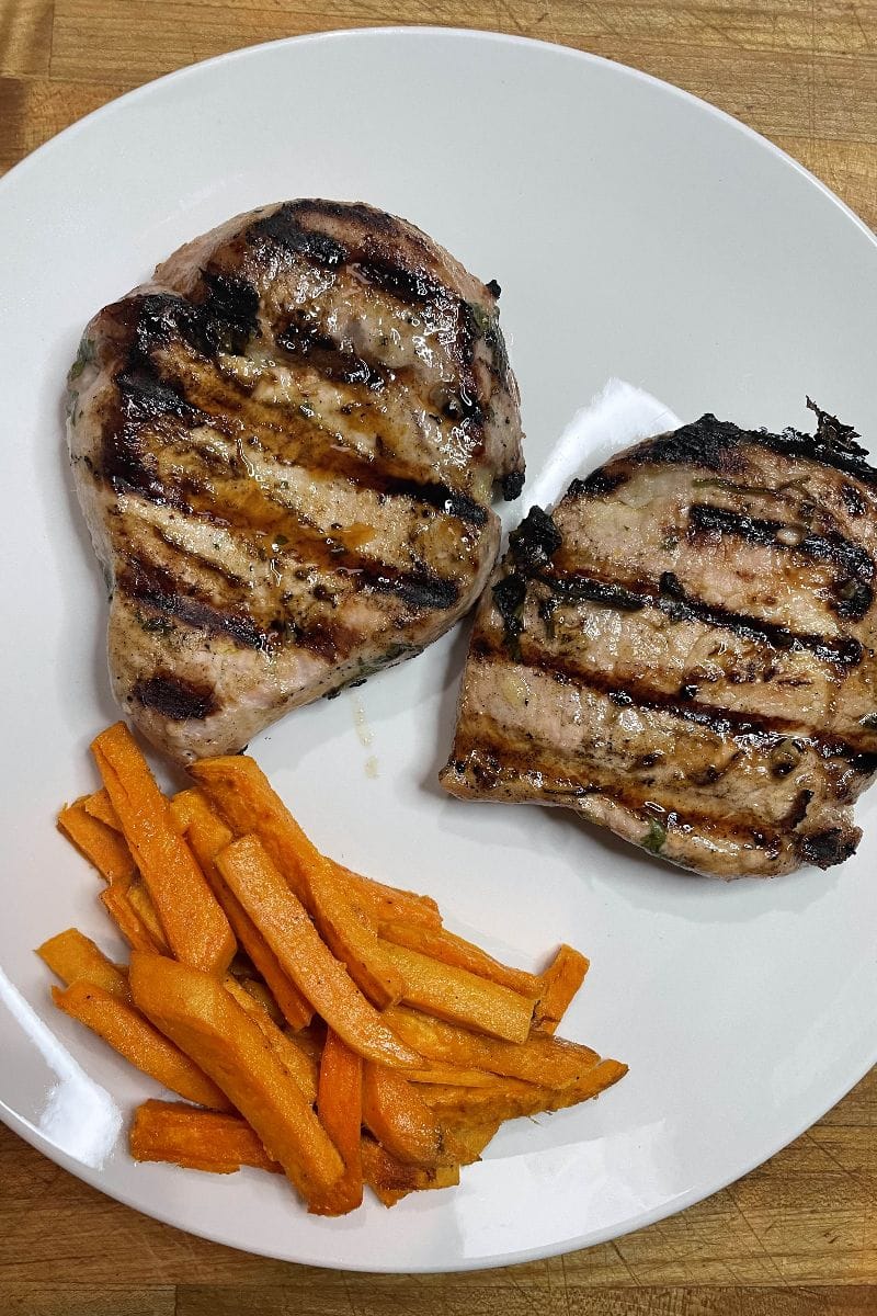 Grilled Cuban pork chops, plated with sweet potato fries.