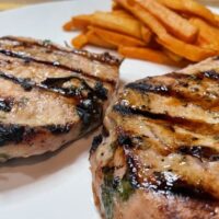 Grilled Cuban pork chops, plated with sweet potato fries.