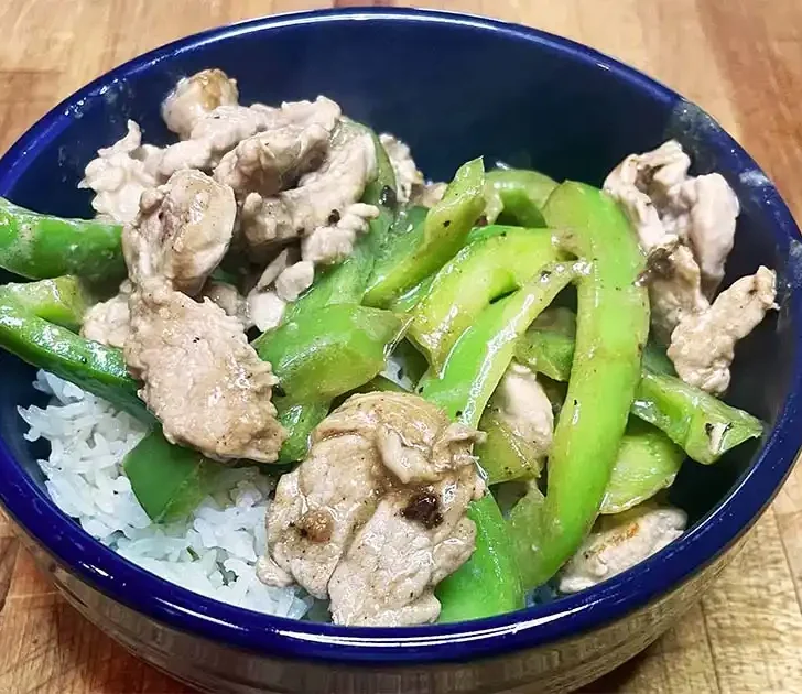 Prepared pork and pepper stir fry over white rice.