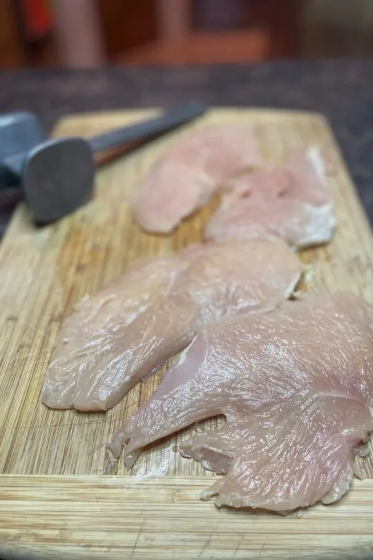 Raw pounded chicken breast on cutting board.