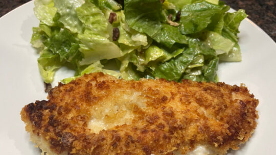 Chicken Romano prepared on plate with salad.