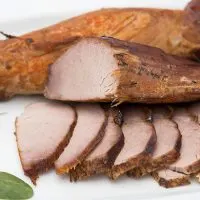 Roasted pork tenderloin, sliced on serving dish.