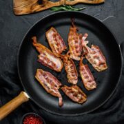 Overhead view of cooked bacon strips in skillet.
