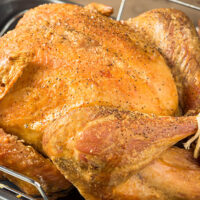 Seasoned turkey cooked in the oven in a roasting pan.
