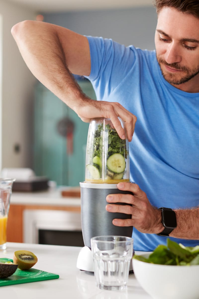 Healthy man makes smoothie as part of a bodybuilder food diet.