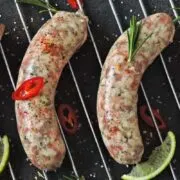 Four Italian sausages cooking on the grill.