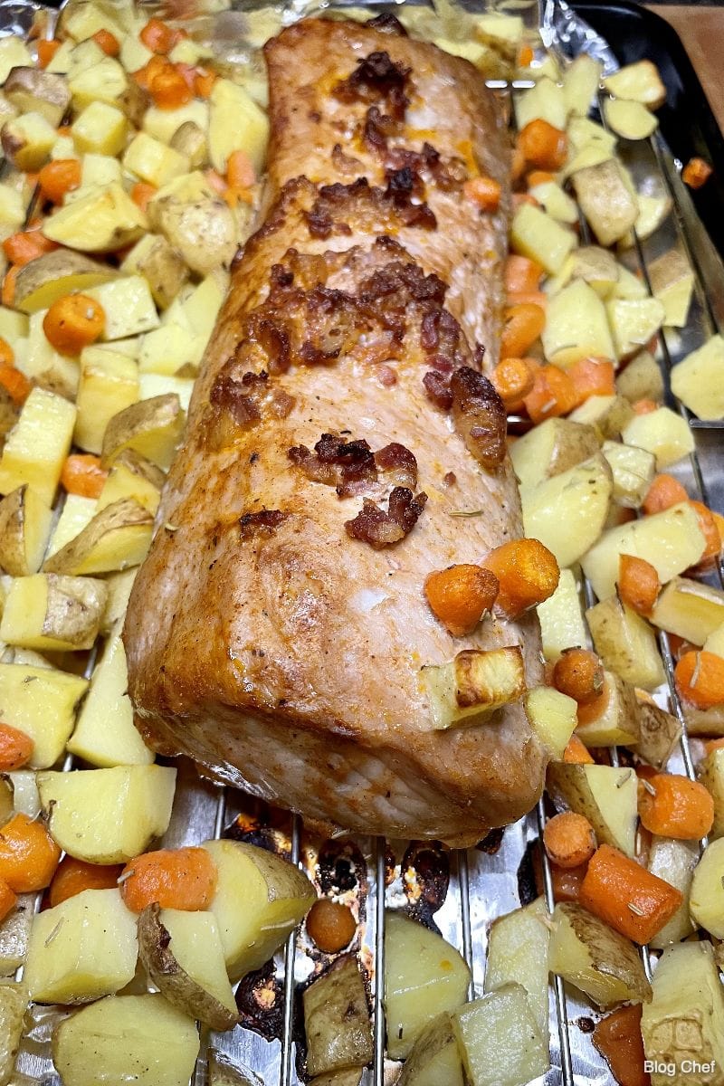 Cooked Smithfield pork tenderloin on roasting rack with vegetables.