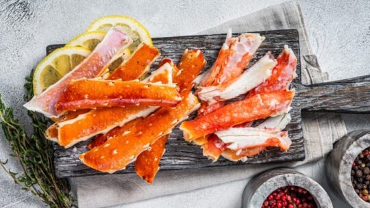 Top view of cooked crab legs on wooden dish.