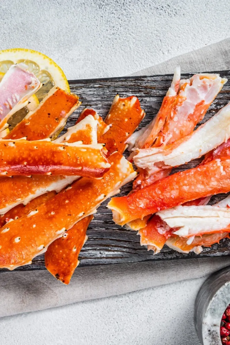 Top view of cooked crab legs on wooden dish.