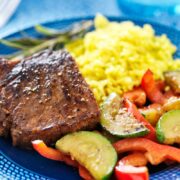 Marinated, oven-baked steak on plate with vegetables and rice.