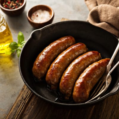 Italian sausage cooked on stove in skillet.