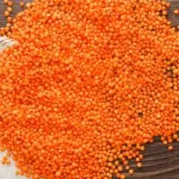 Raw red lentils on wood surface.