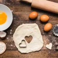 Eggs, dough, and rolling pin on cutting board to represent what can I substitute for eggs in baking.
