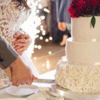 Newly married couple slices wedding cake.