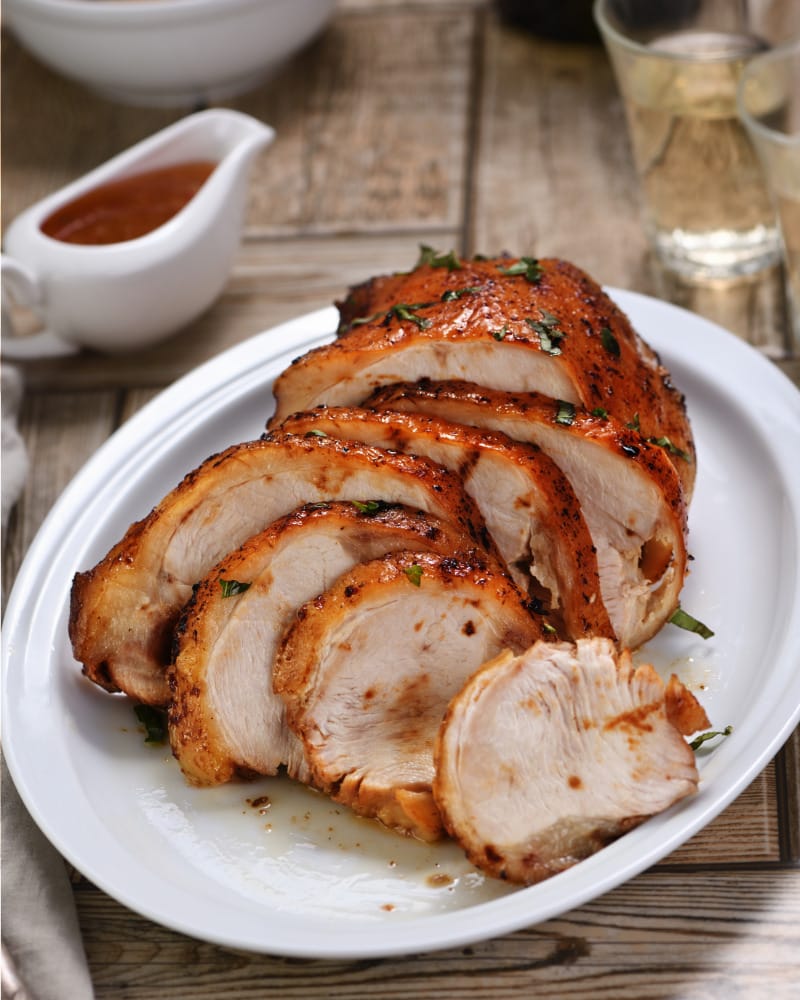 Sliced, roasted turkey breast on plate to represent how to cook a Butterball turkey breast.