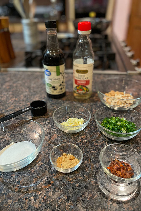 Ingredients for Kung Pao chicken, measured into bowls and sitting on a granite counter.
