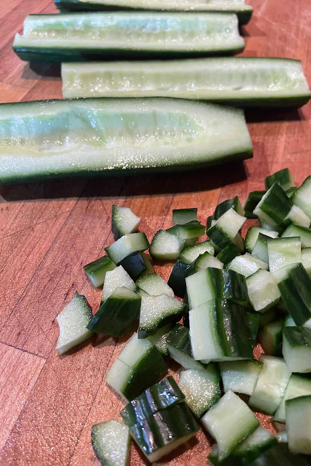 Diced and seeded English cucumbers on a cutting board.