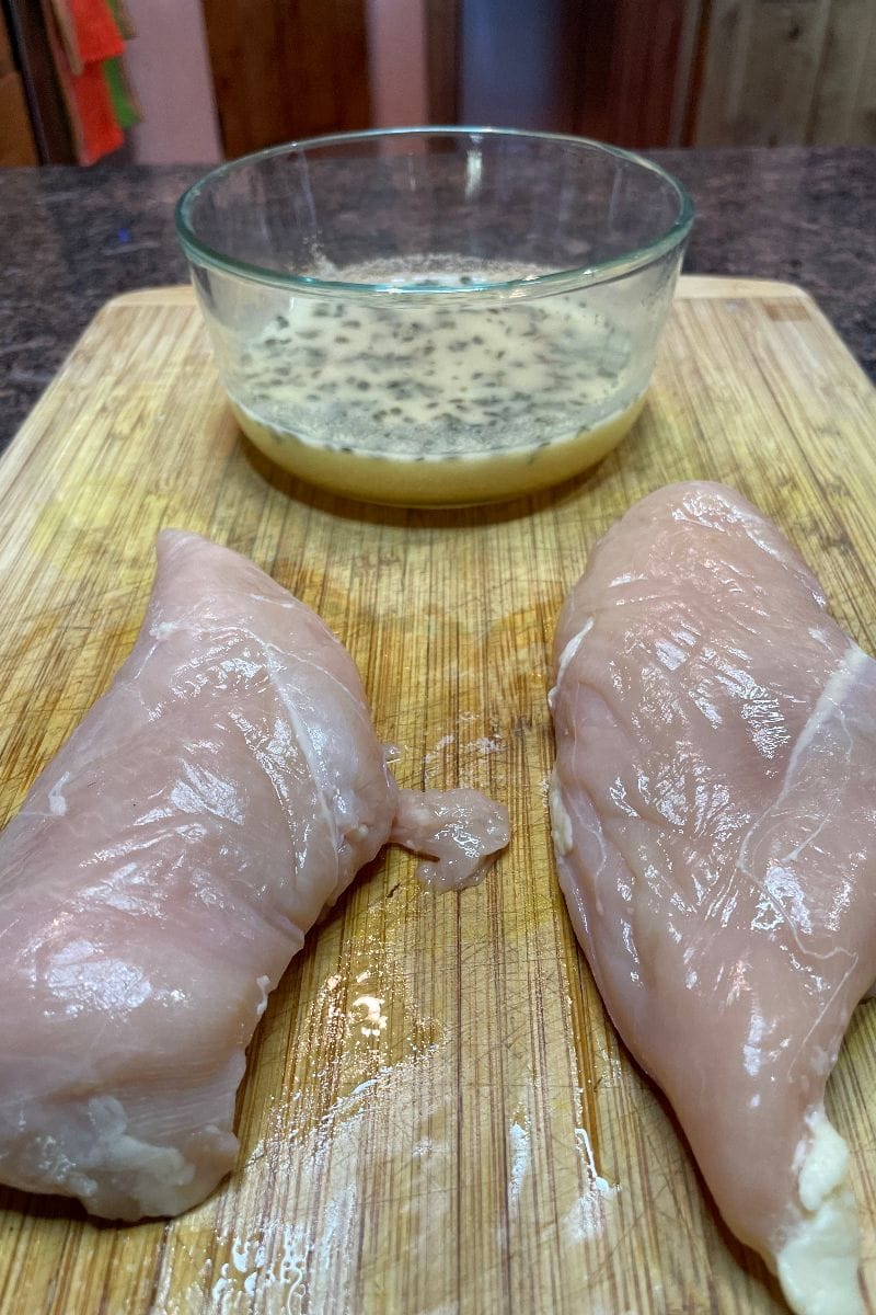 Boneless, skinless chicken breasts on cutting board with artisan grilled chicken recipe marinade.