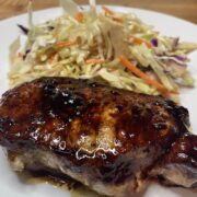 Close up view of Korean pork chop on plate with Asian slaw.