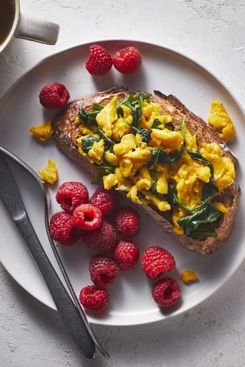 Overhead view of eggs on toast with raspberries. 