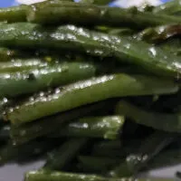 Oven roasted green beans on white and blue plate.