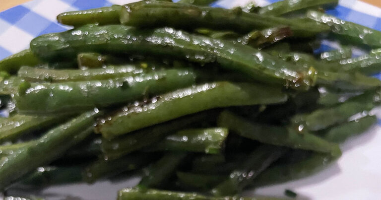 Oven roasted green beans on white and blue plate.