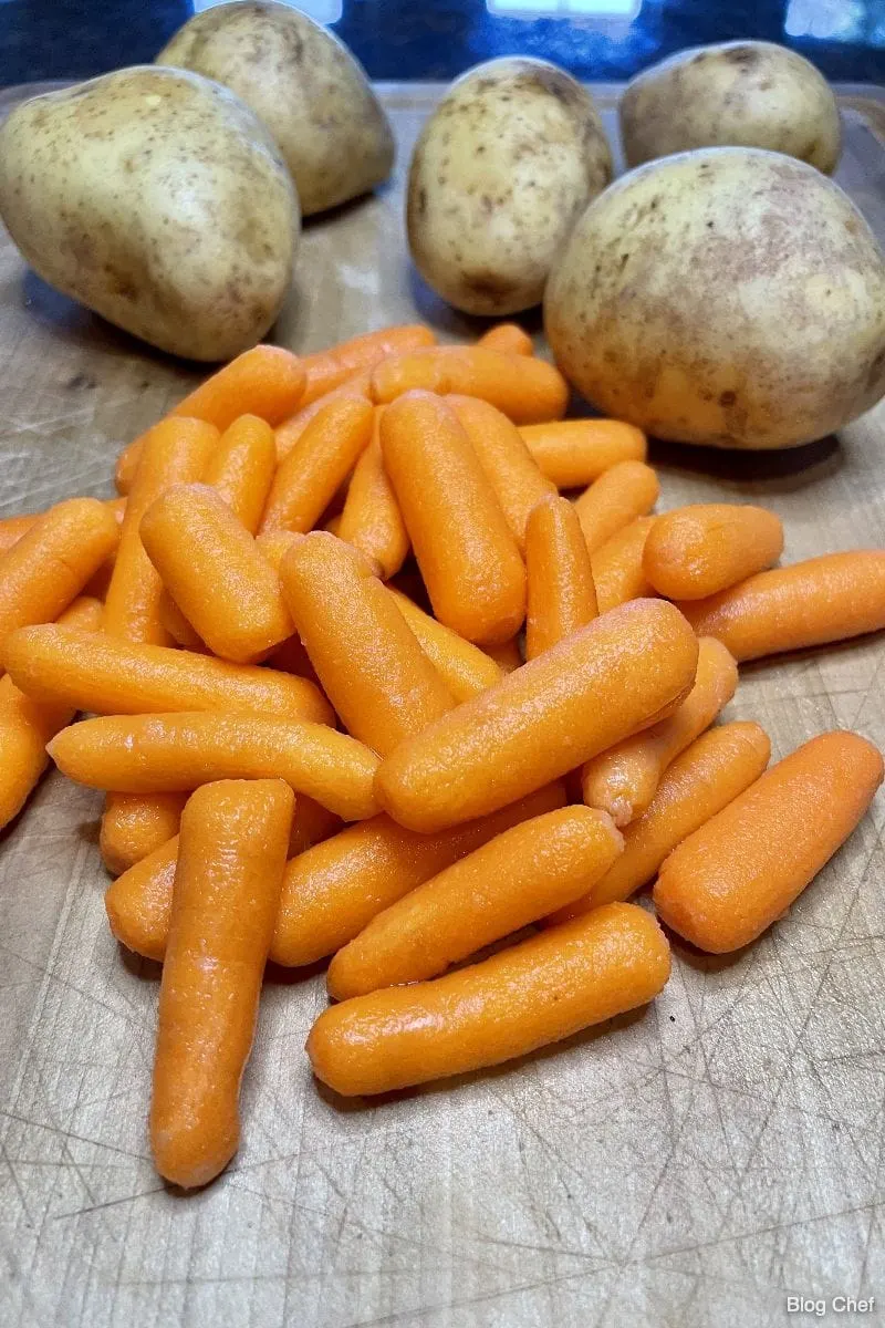 Baby carrots and potatoes on a cutting board. 